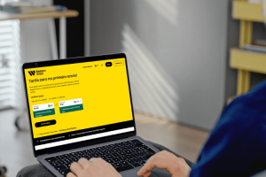 Pessoa acessa o site da Western Union para viagem em um notebook para simular envio internacional de dinheiro.