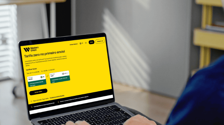 Pessoa acessa o site da Western Union para viagem em um notebook para simular envio internacional de dinheiro.