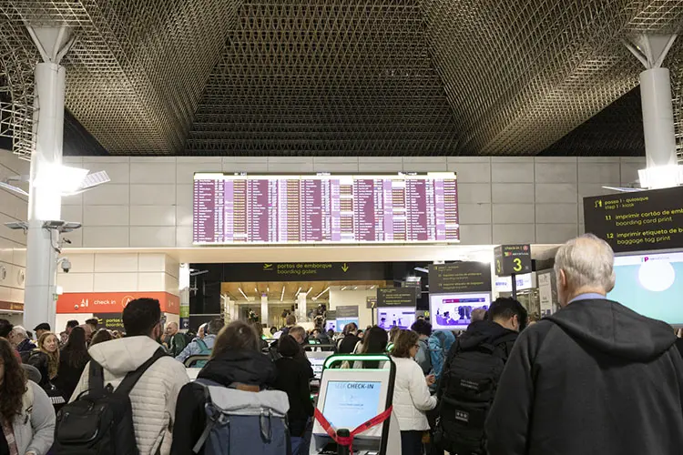 Viajantes na área de embarque do Aeroporto Internacional de Lisboa, Portugal.