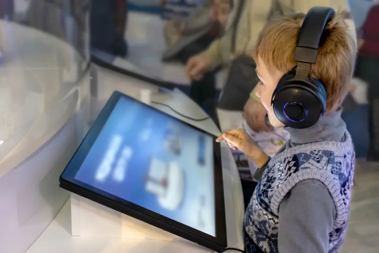 Menino explorando recursos do museu pelo tablet.
