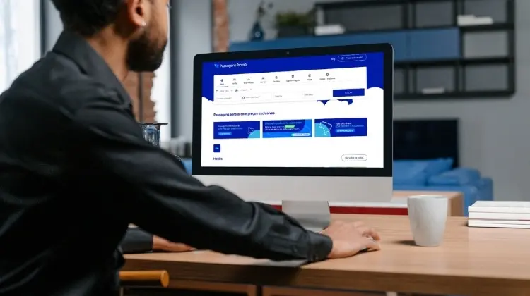 Homem utiliza computador com o site Passagens Promo aberto na tela.