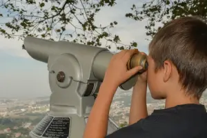 criança observando cidade a partir de telescópio