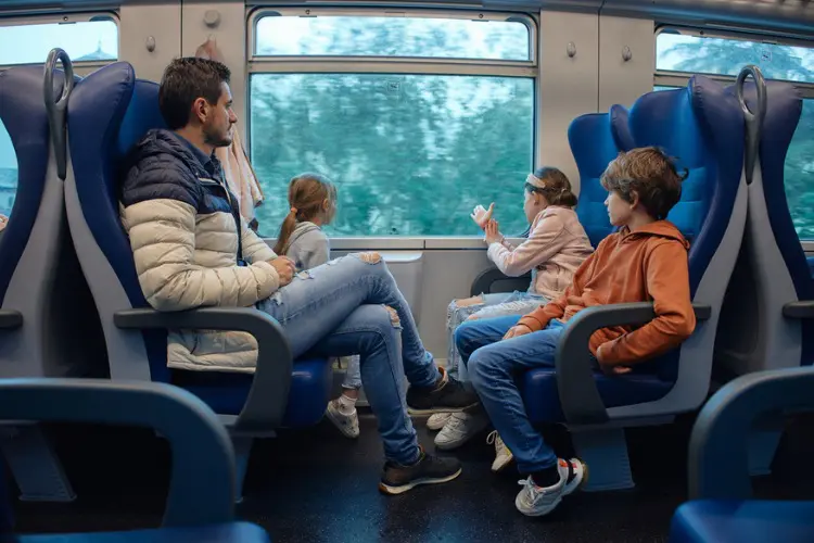 Pai usando trem para viajar pela Itália com crianças.