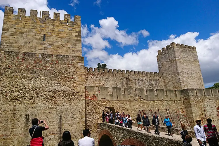 Turistas explorando as antigas muralhas do Castelo de São Jorge