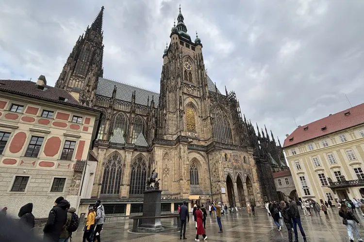 Turistas em frente ao Castelo de Praga em dia nublado.