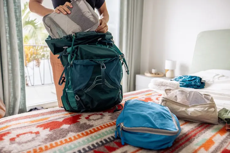 Pessoa organiza roupas em uma mochila de viagem.