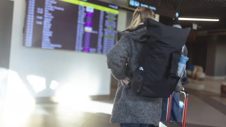 Passageira em aeroporto, com mochila para viagem de avião.