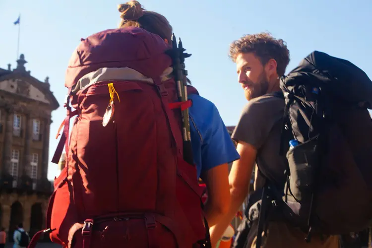 Dois jovens com mochilas de viagem, em dia de sol