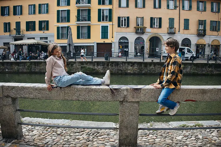 Duas crianças sorrindo conversando na grade da ponte em Milão.