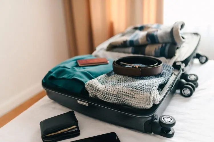 Mala de viagem com roupas sobre uma cama