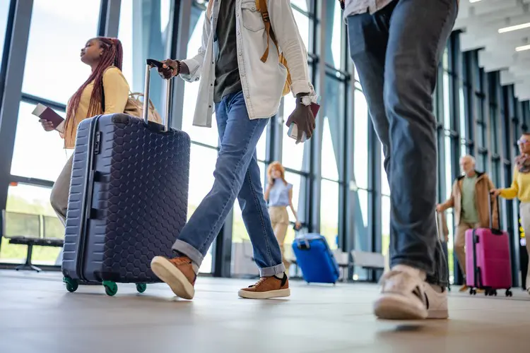 Grupo de pessoas andando com malas de rodinha no aeroporto