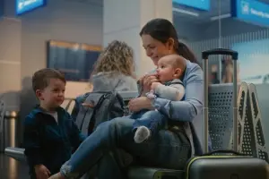Mãe aguarda o embarque com os dois filhos representando a realidade de quem voa sozinha com crianças pequenas