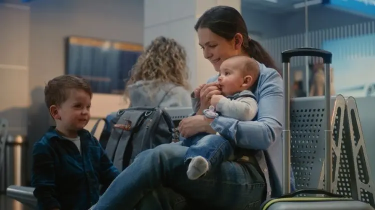 Mãe aguarda o embarque com os dois filhos representando a realidade de quem voa sozinha com crianças pequenas