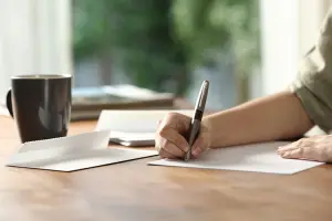 Mulher escrevendo carta convite para receber convidado na Europa.