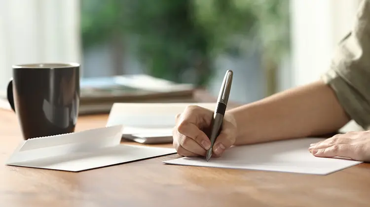 Mulher escrevendo carta convite para receber convidado na Europa.