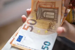 Pessoa segurando notas de 50 euros em mãos.