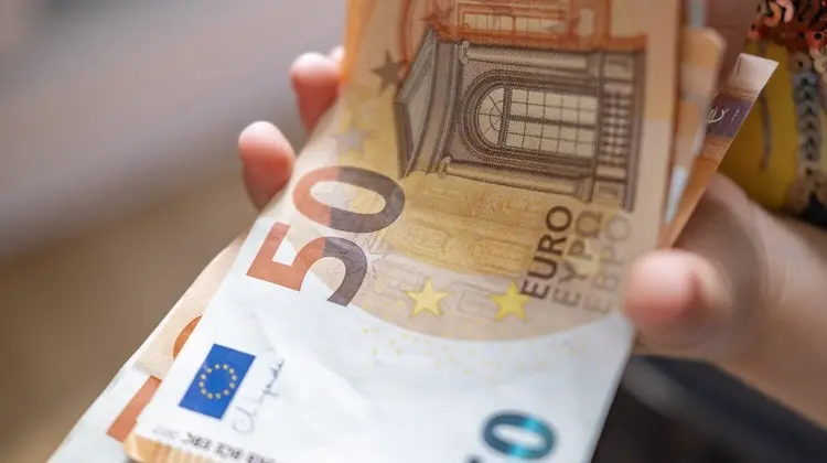 Pessoa segurando notas de 50 euros em mãos.