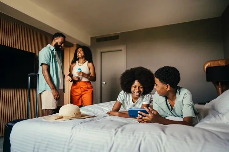 Grupo de amigos reunidos em quarto de hotel comprando passagem aérea