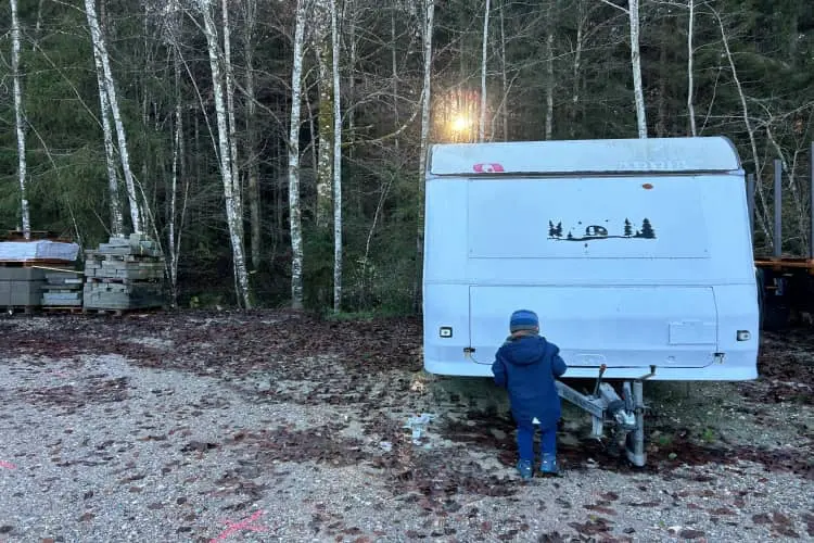 Trailer passando o inverno estacionando em uma fazenda na Alemanha com menino virado de costas olhando o veículo