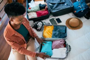 Pessoa organizando roupas em mala usando organizador de mala de viagem.