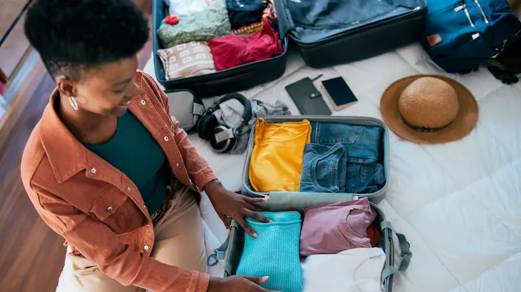 Pessoa organizando roupas em mala usando organizador de mala de viagem.
