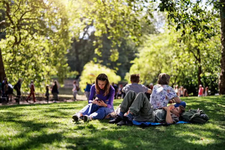 Parque de Londres com crianças sentadas na grama