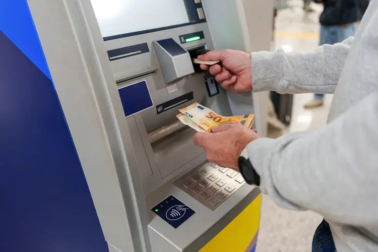 Pessoa retirando notas de euro em um caixa eletrônico europeu.