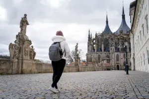 Turista de costas caminhando em rua histórica em direção à Catedral de Santa Bárbara, na República Tcheca.