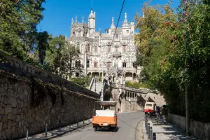 Rua em Sintra com castelo ao fundo e carros passando em um bate e volta de Lisboa.