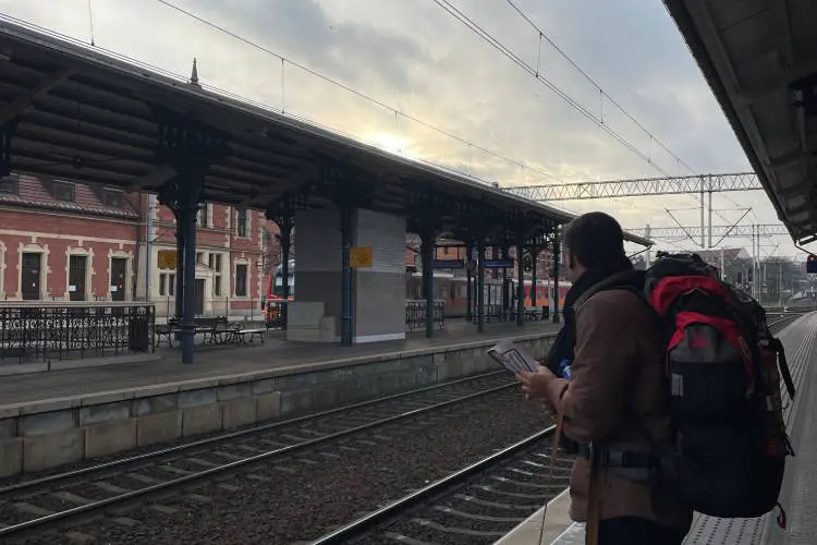 Homem com mochila grande de viagem nas costas em estação de trem.